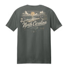 A dark gray crewneck t-shirt shown from the back, featuring a vintage-style North Carolina coastal graphic in cream and gold tones with the text 'North Carolina' and 'The Blue State'.