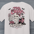 Close-up of Back Porch Apparel Too Cute to Spook Halloween design with mummy, pink bow, pumpkin and cowboy boots