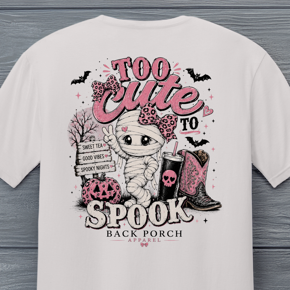 Close-up of Back Porch Apparel Too Cute to Spook Halloween design with mummy, pink bow, pumpkin and cowboy boots