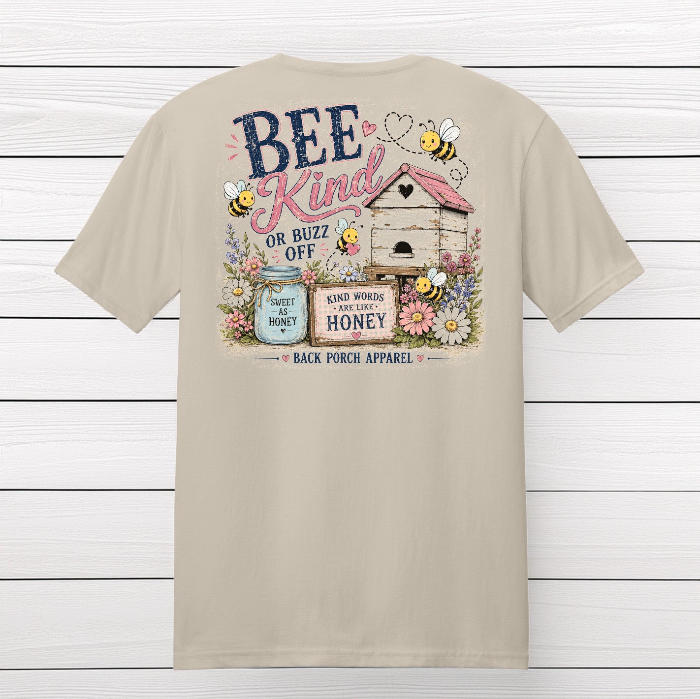 Back view of the Bee Kind or Buzz Off graphic t-shirt hanging against a white wood background.