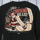 A black long-sleeve crewneck sweatshirt featuring a large Christmas-themed graphic on the back. The graphic shows Santa Claus holding a long scroll with a list of names under the text 'He's CHECKING HIS LIST' in red and white lettering.