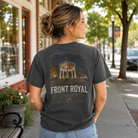 A woman stands on a city sidewalk wearing a faded charcoal gray graphic T-shirt. The back of the shirt features a distressed print of a gazebo with the text 'FRONT ROYAL Virginia' and smaller text below.