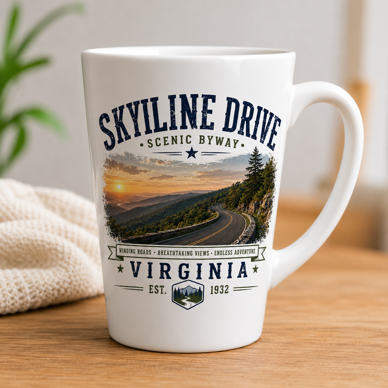 White ceramic latte mug featuring a vintage Skyline Drive Scenic Byway design with a winding mountain road, Blue Ridge Mountain sunset, and Shenandoah National Park Virginia typography.