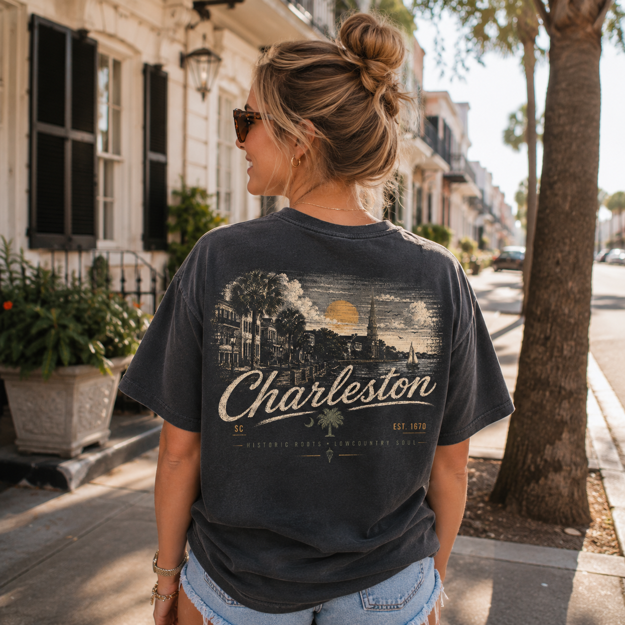 A woman wearing a charcoal gray graphic t-shirt with a vintage Charleston print, standing on a sunny city street.