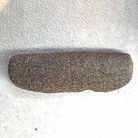 A dark brown textured stone or granite bar, possibly a sharpening stone or natural tool, lying horizontally on a white textured fabric background.