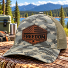 Gray and olive digital camouflage trucker hat with tan mesh back and dark brown leather Freedom American flag patch by Back Porch Apparel.