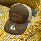 Front Royal Virginia leather patch Richardson 112 trucker hat resting on hay bales in warm golden farm lighting.