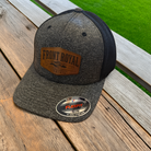 Front Royal Virginia leather patch Flexfit trucker hat resting on a weathered wooden deck with a green lawn in the background.