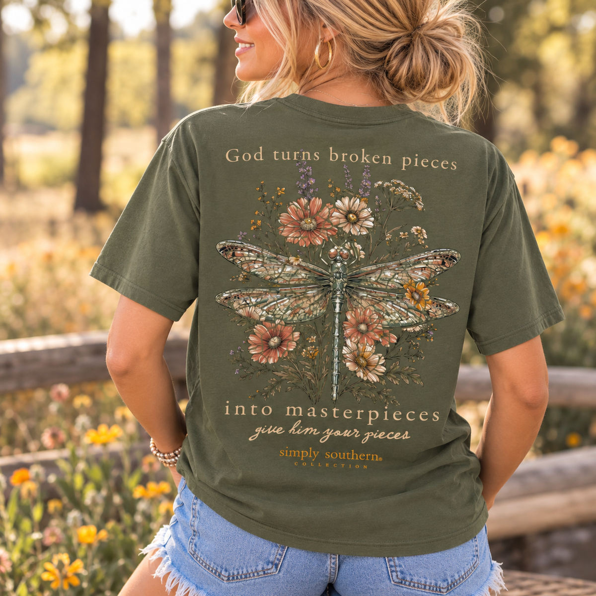 Woman wearing an olive green Simply Southern dragonfly short sleeve T-shirt with wildflowers and God Turns Broken Pieces Into Masterpieces back graphic.