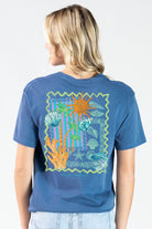 Model wearing a Simply Southern overcast blue mineral washed t-shirt with colorful reef design on the back