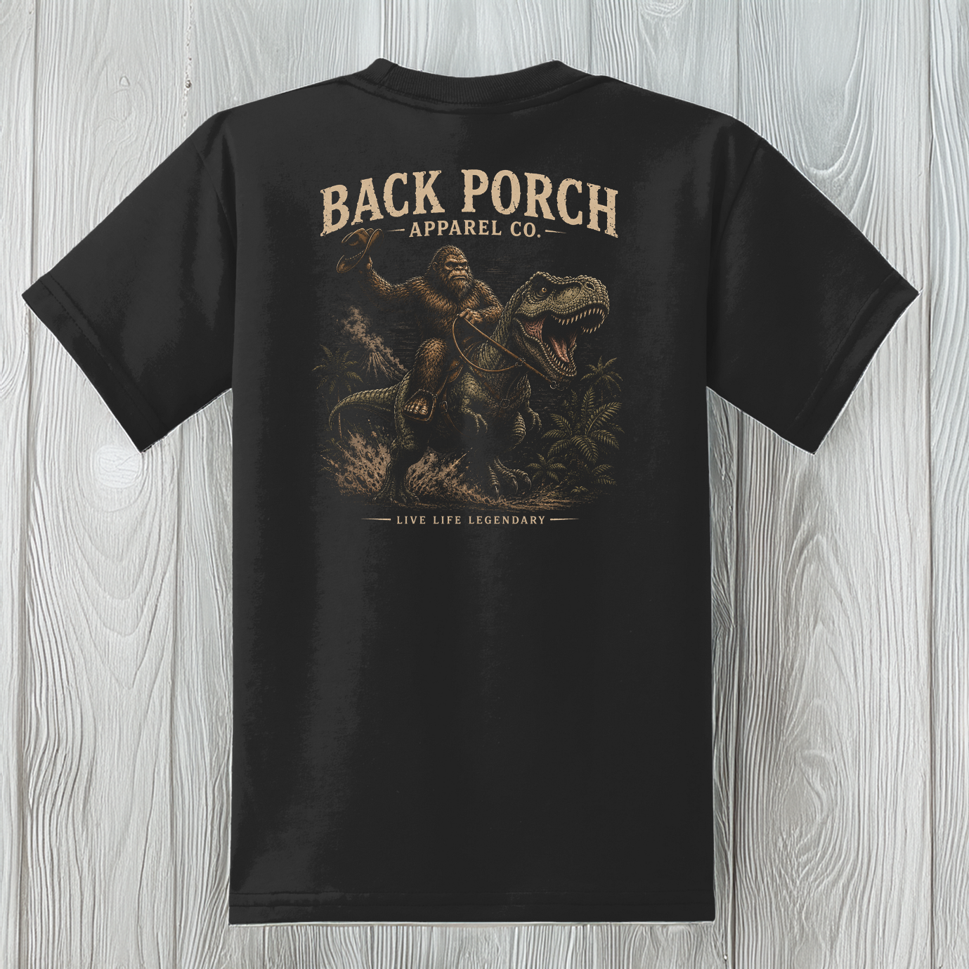 Youth Bigfoot Riding T-Rex t-shirt on a black 50/50 blend tee featuring a vintage dinosaur graphic.