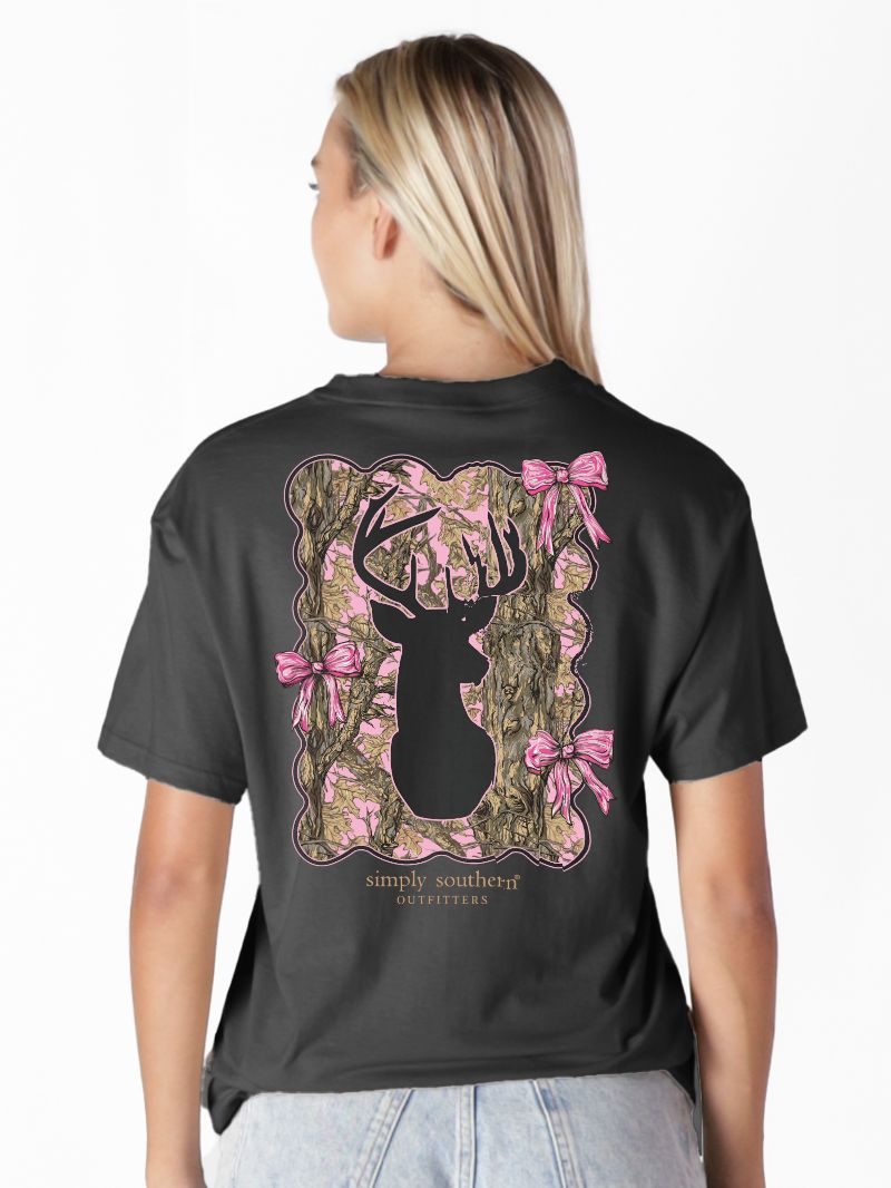 Model wearing Simply Southern black t-shirt with pink camo deer silhouette and bow design on back