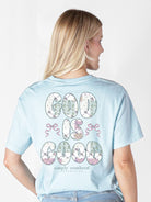 Model wearing Simply Southern ice blue God Is Good t-shirt showing floral letter and bow back design