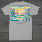 Simply Southern “His Mercies Are New Every Morning” short sleeve T-shirt featuring a colorful coastal sunrise with palm trees and ocean waves on a gray background