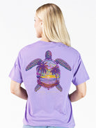 Model wearing Simply Southern grape t-shirt with colorful sea turtle sunset back graphic