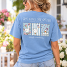 Woman wearing a Simply Southern Walking by Faith Tripping Constantly mineral washed T-shirt in Faded Blue featuring three white geese with pink bows and floral backgrounds.
