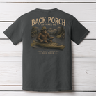 Bigfoot kayaking graphic t-shirt on Comfort Colors garment-dyed tee featuring Sasquatch paddling a kayak through a mountain river with Back Porch Apparel branding