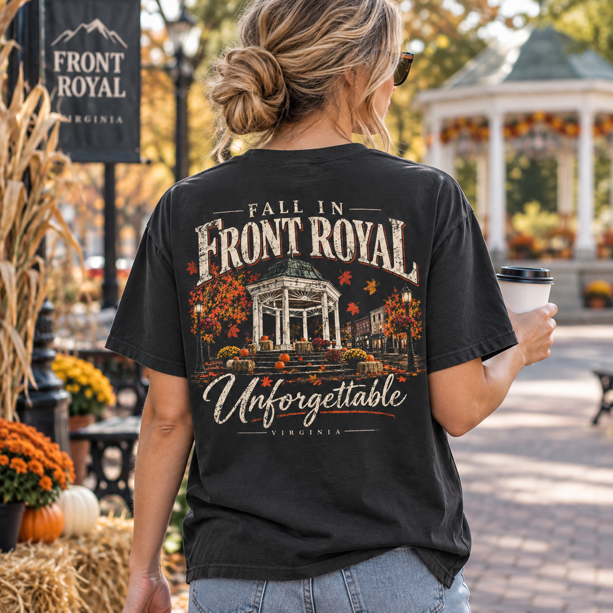Woman wearing a Fall in Front Royal Virginia Comfort Colors T-shirt while holding coffee near the gazebo in an autumn setting.