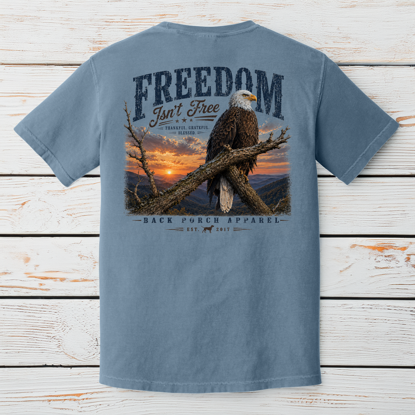 Patriotic bald eagle artwork with Freedom Isn't Free message overlooking a mountain sunrise and scenic landscape