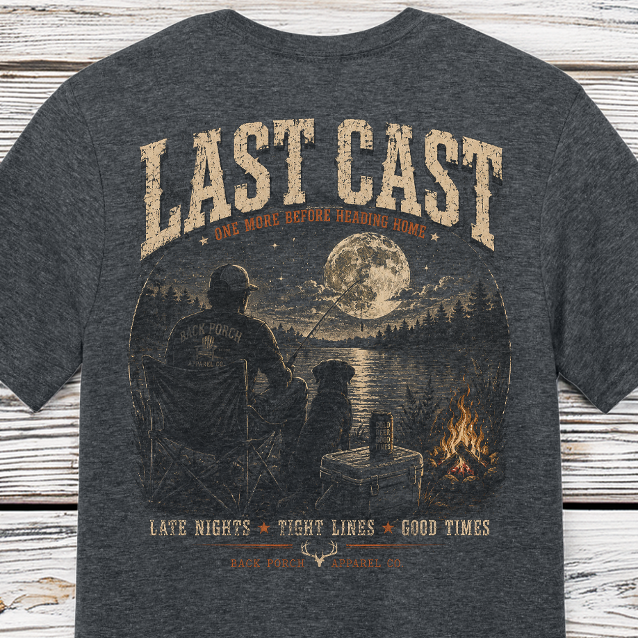 Last Cast fishing graphic t-shirt on Comfort Colors garment-dyed tee featuring a fisherman, loyal dog, moonlit lake, and campfire scene