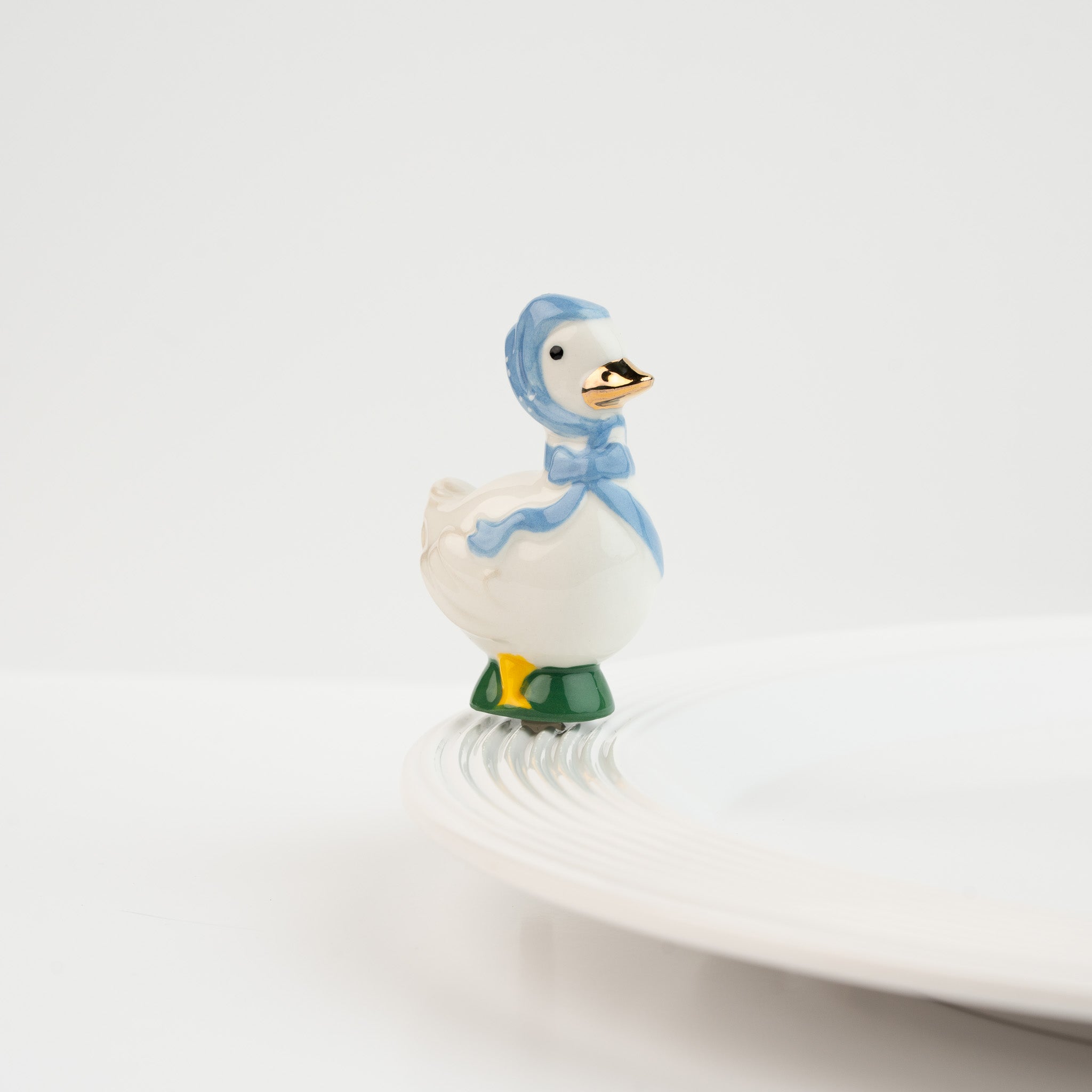 Nora Fleming Porch Pal goose mini wearing blue bonnet on Nora Fleming platter