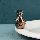 Nora Fleming Luxe Hospitality metallic bronze pineapple mini on a white Nora Fleming serving piece