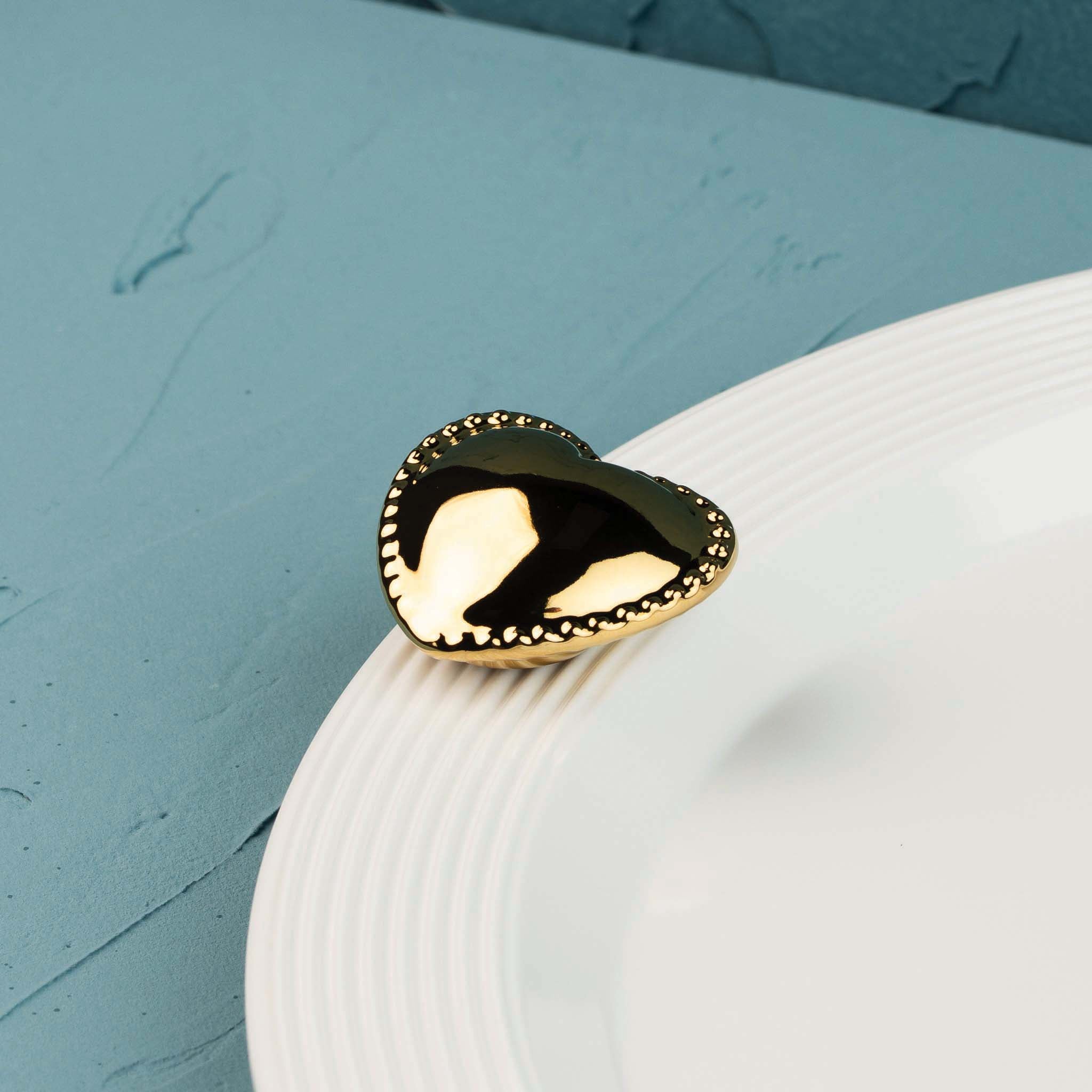 Nora Fleming Luxe Love metallic gold heart mini displayed on a white Nora Fleming serving piece