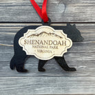 Handmade Shenandoah National Park bear ornament featuring a black bear silhouette, engraved wood badge, and red ribbon on a rustic gray wood background.